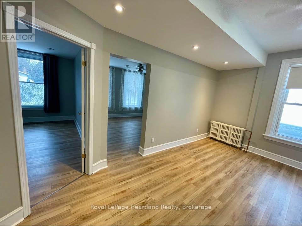 A room with wooden flooring and a window with blinds.