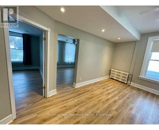 A room with wooden flooring and a window with blinds.
