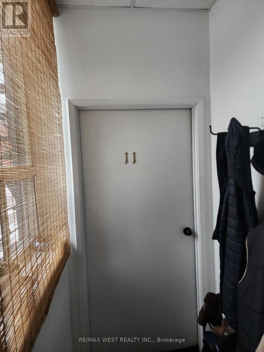 A white door with the number 11 on it is in a room with a coat hanging on the wall.