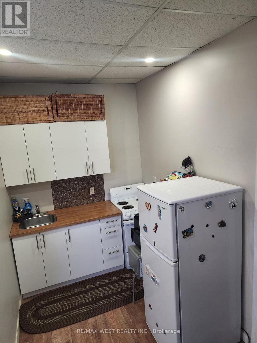 A small kitchen with a white fridge and a brown mat on the floor.
