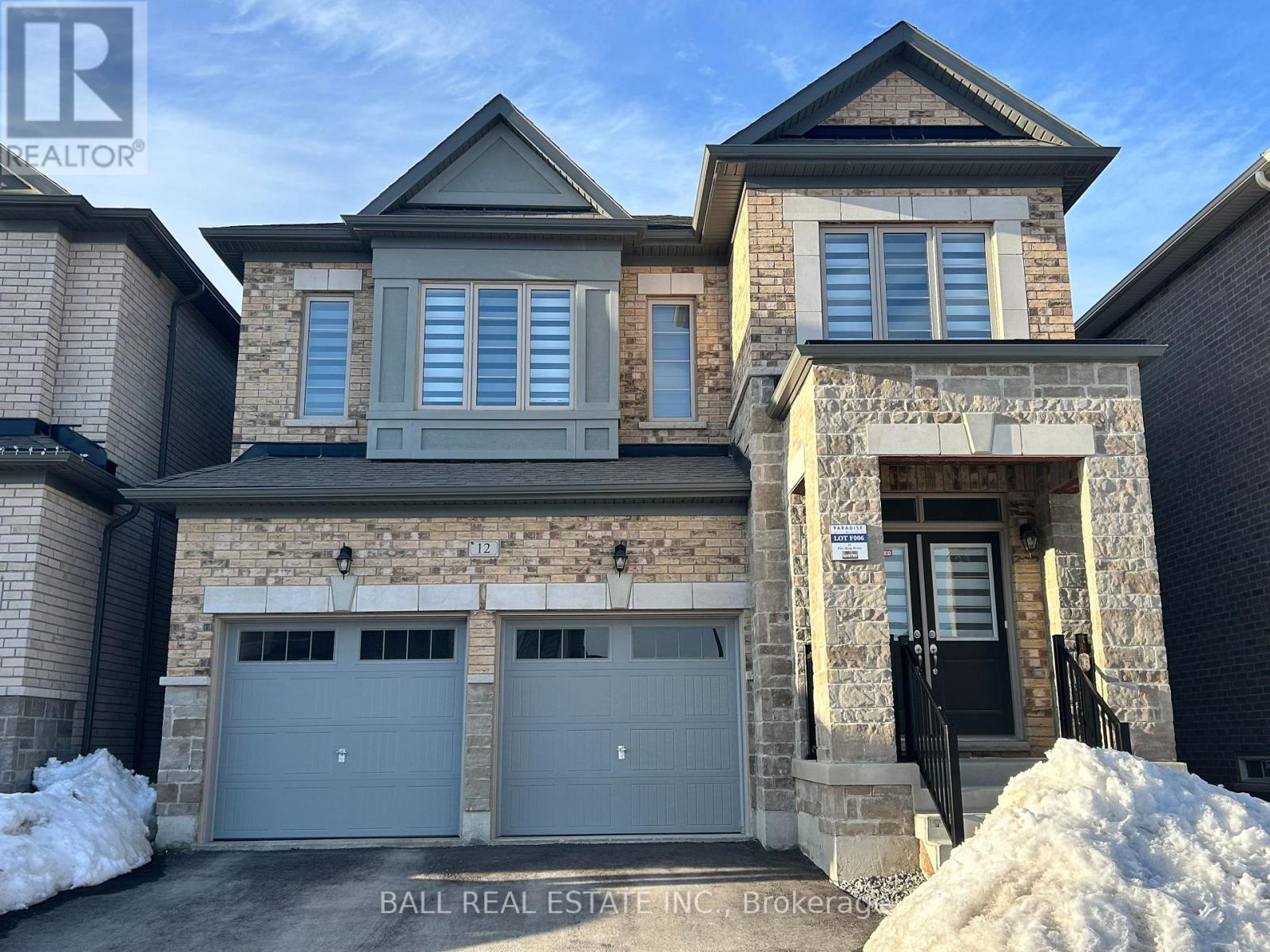 A large house with a stone facade and two garages is for sale.