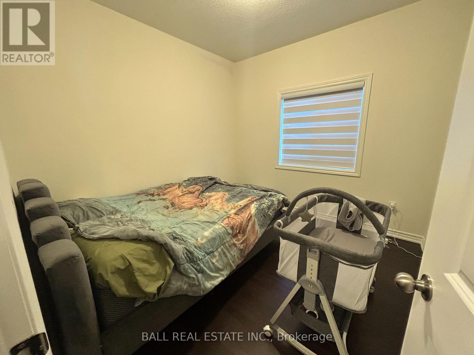A small bedroom with a bed, a chair, and a window with blinds.