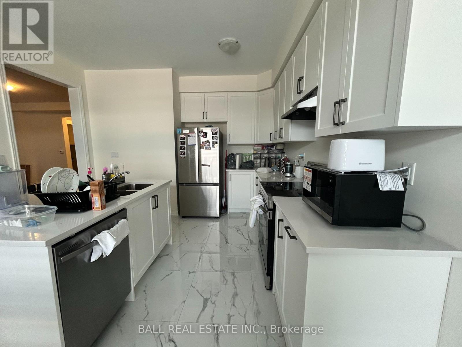 A kitchen with a marble floor and white cabinets.