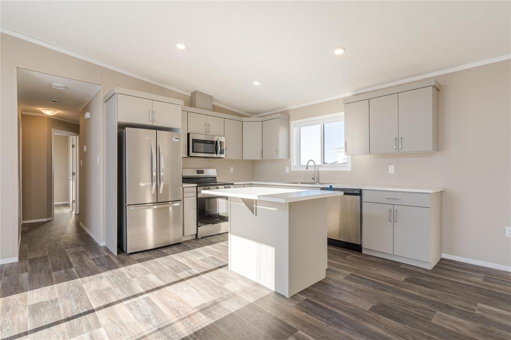 A kitchen with a refrigerator, microwave, and oven.