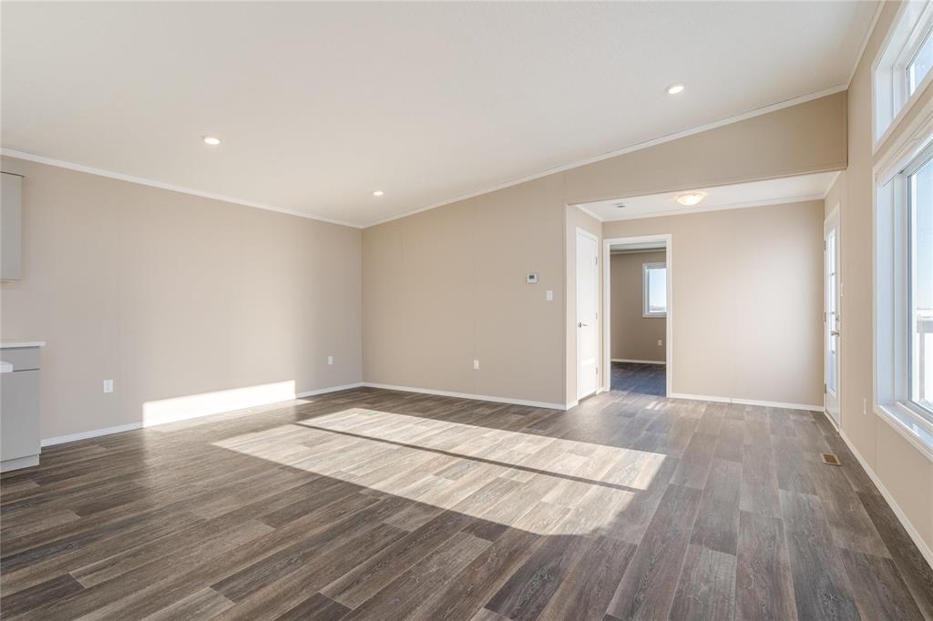 A spacious room with wooden flooring and a rug in the middle.