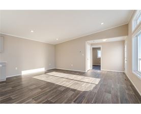 A spacious room with wooden flooring and a rug in the middle.