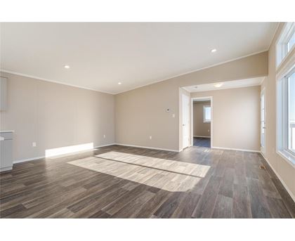 A spacious room with wooden flooring and a rug in the middle.