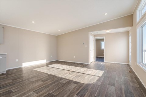 A spacious room with wooden flooring and a rug in the middle.