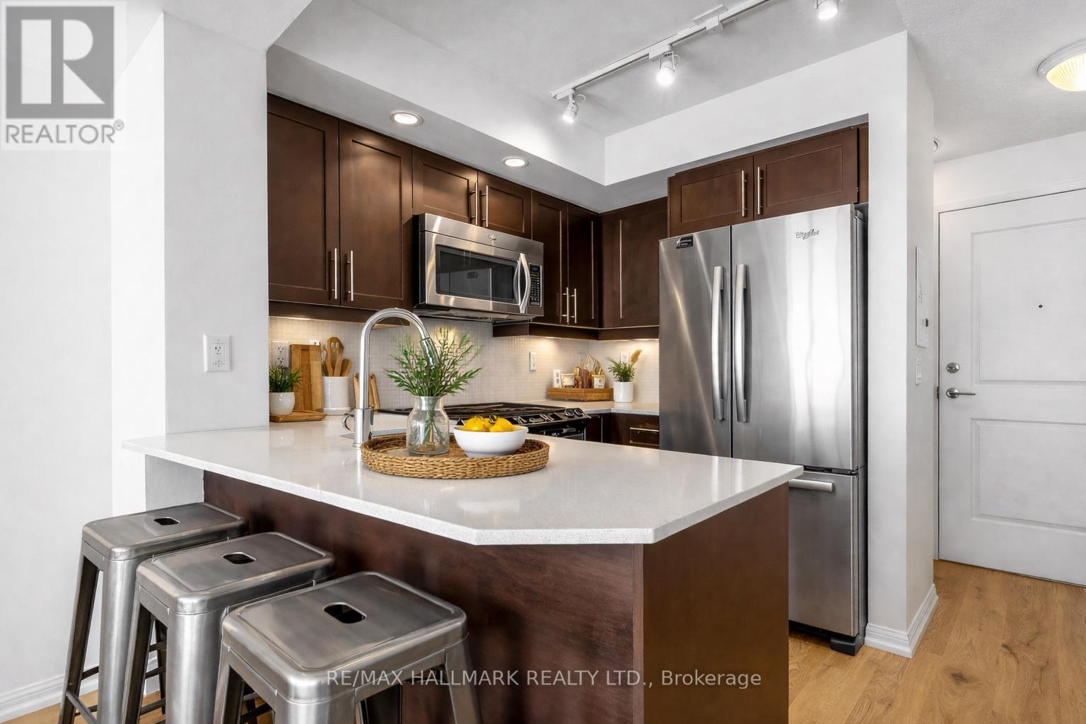 A modern kitchen with dark brown cabinets and stainless steel appliances.