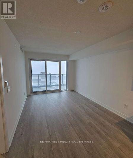 A room with wooden flooring and a sliding glass door leading to a balcony.