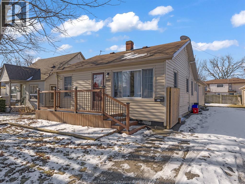 A house with a snow-covered ground and a wooden deck.