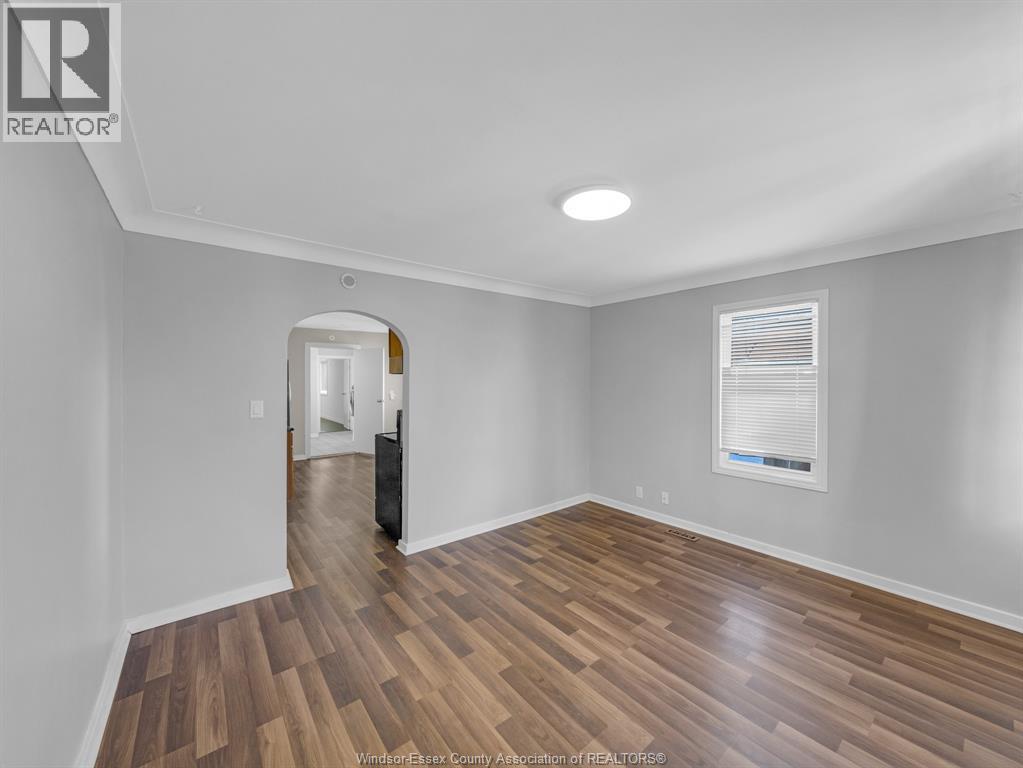 A room with wooden flooring and a window with blinds.