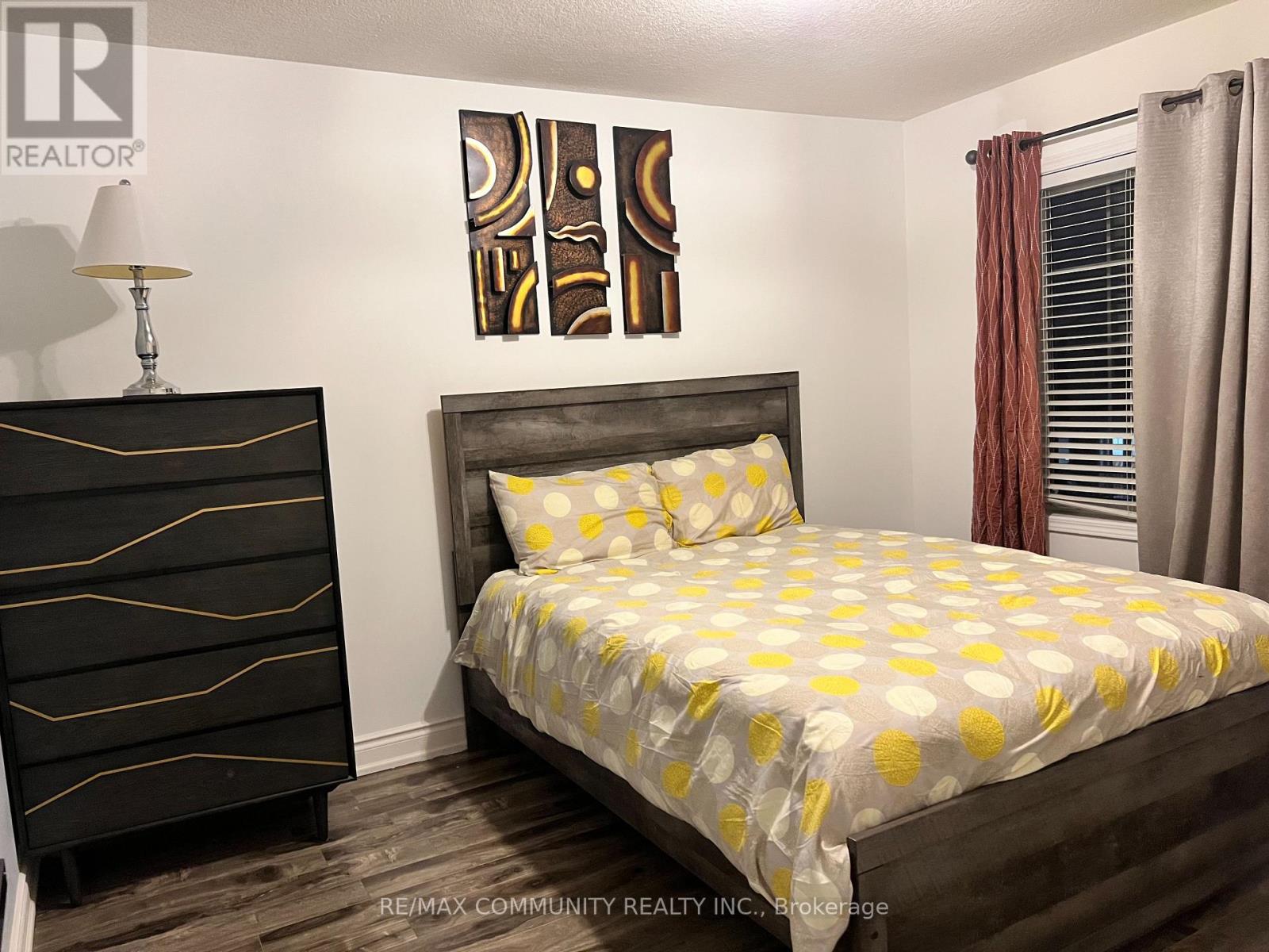 A bedroom with a bed, nightstand, and artwork.
