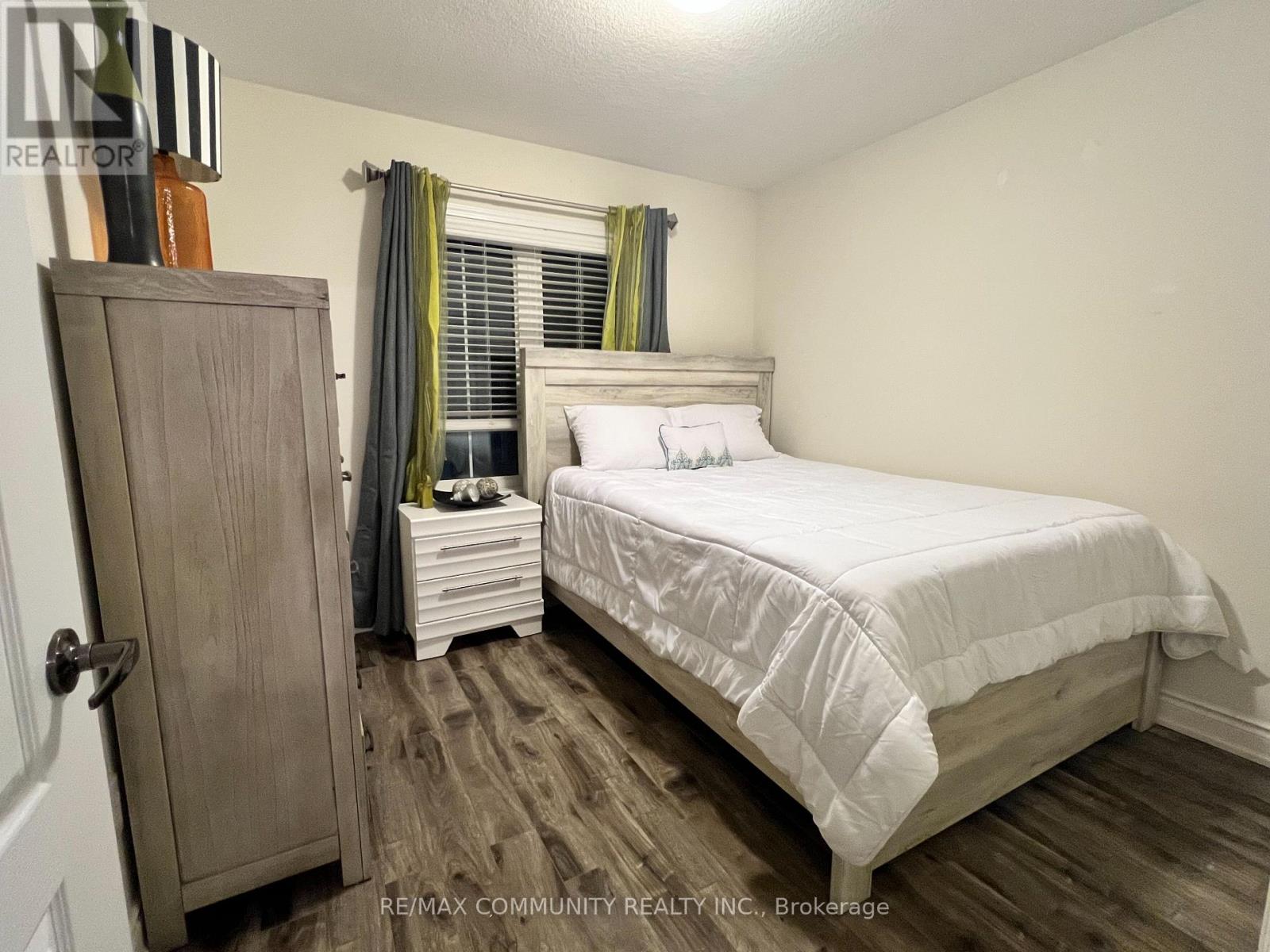 A bedroom with a bed, nightstand, and wardrobe.