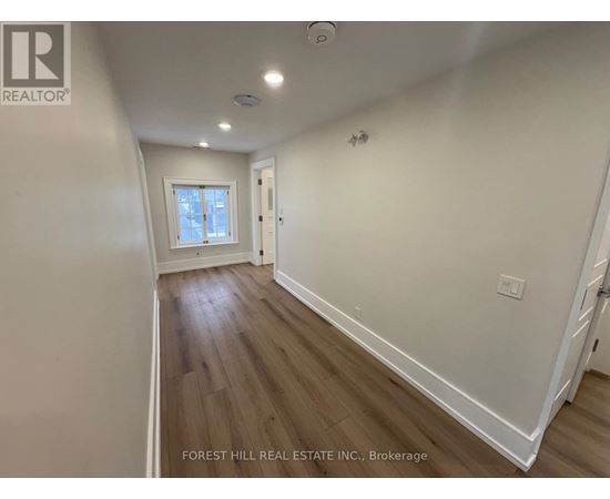 A room with wooden floors and white walls, with a window and a door visible.