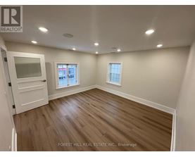 A room with wooden flooring and two windows.