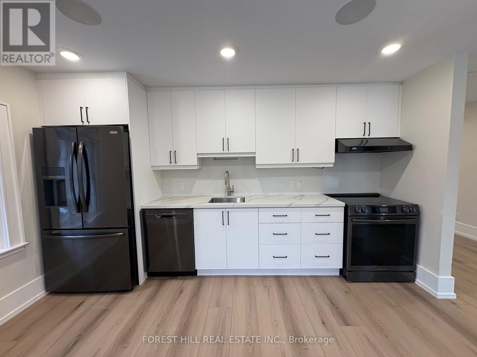 A kitchen with white cabinets and black appliances.