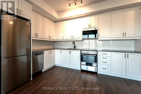 A kitchen with white cabinets and a stainless steel refrigerator.