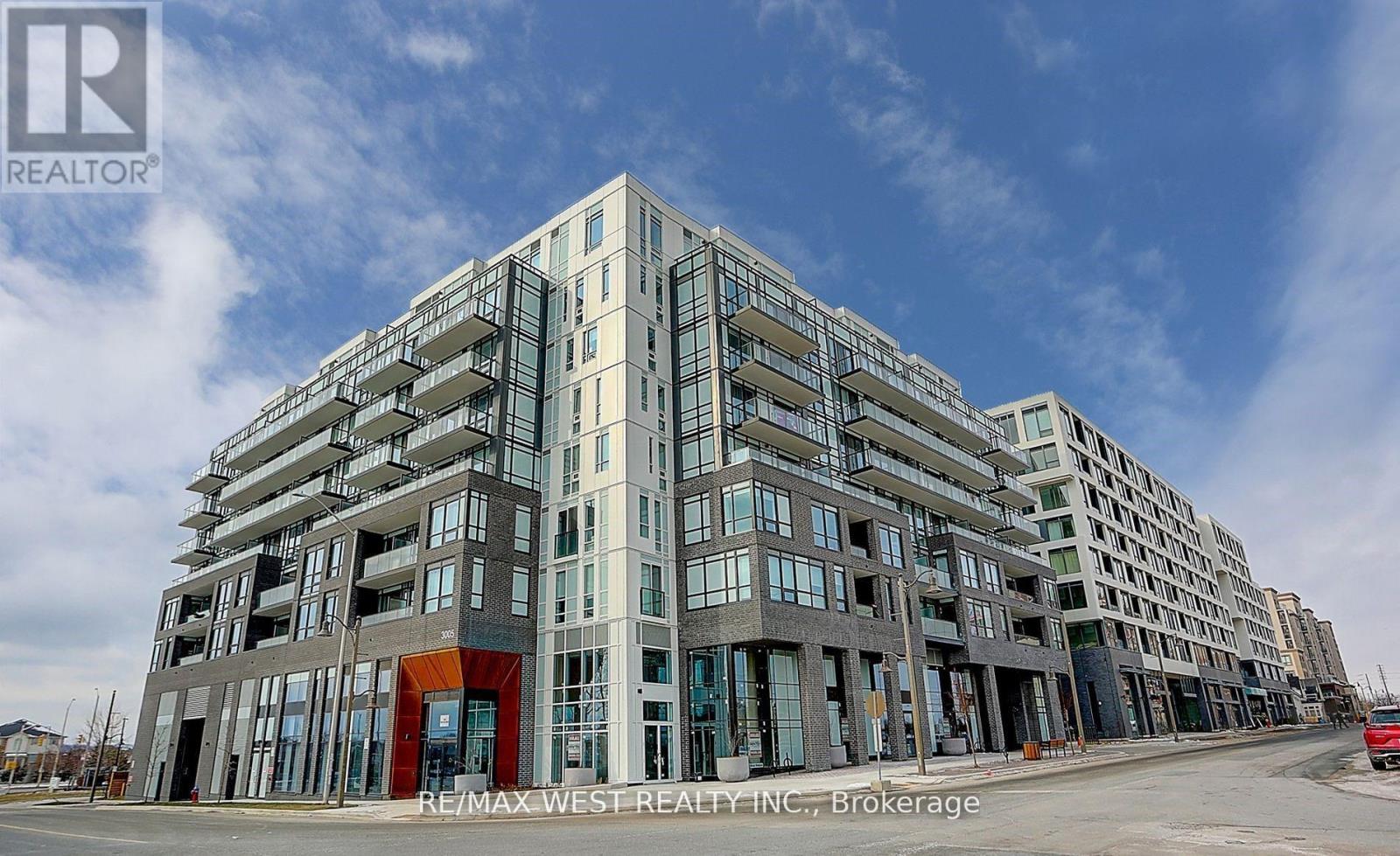 A large multi-story building with a mix of glass and solid panels, with a red entrance, is under construction.