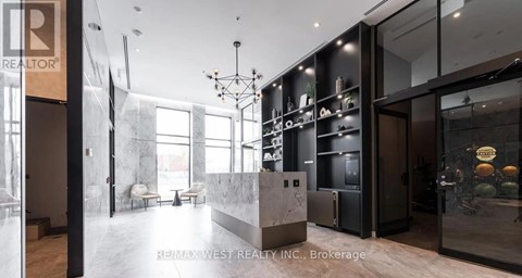 A modern kitchen with a marble countertop and a refrigerator with a glass door.