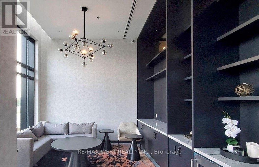 A modern living room with a grey sofa, a round table, and a chandelier.