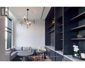A modern living room with a grey sofa, a round table, and a chandelier.