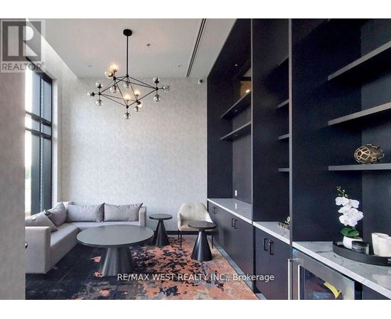 A modern living room with a grey sofa, a round table, and a chandelier.