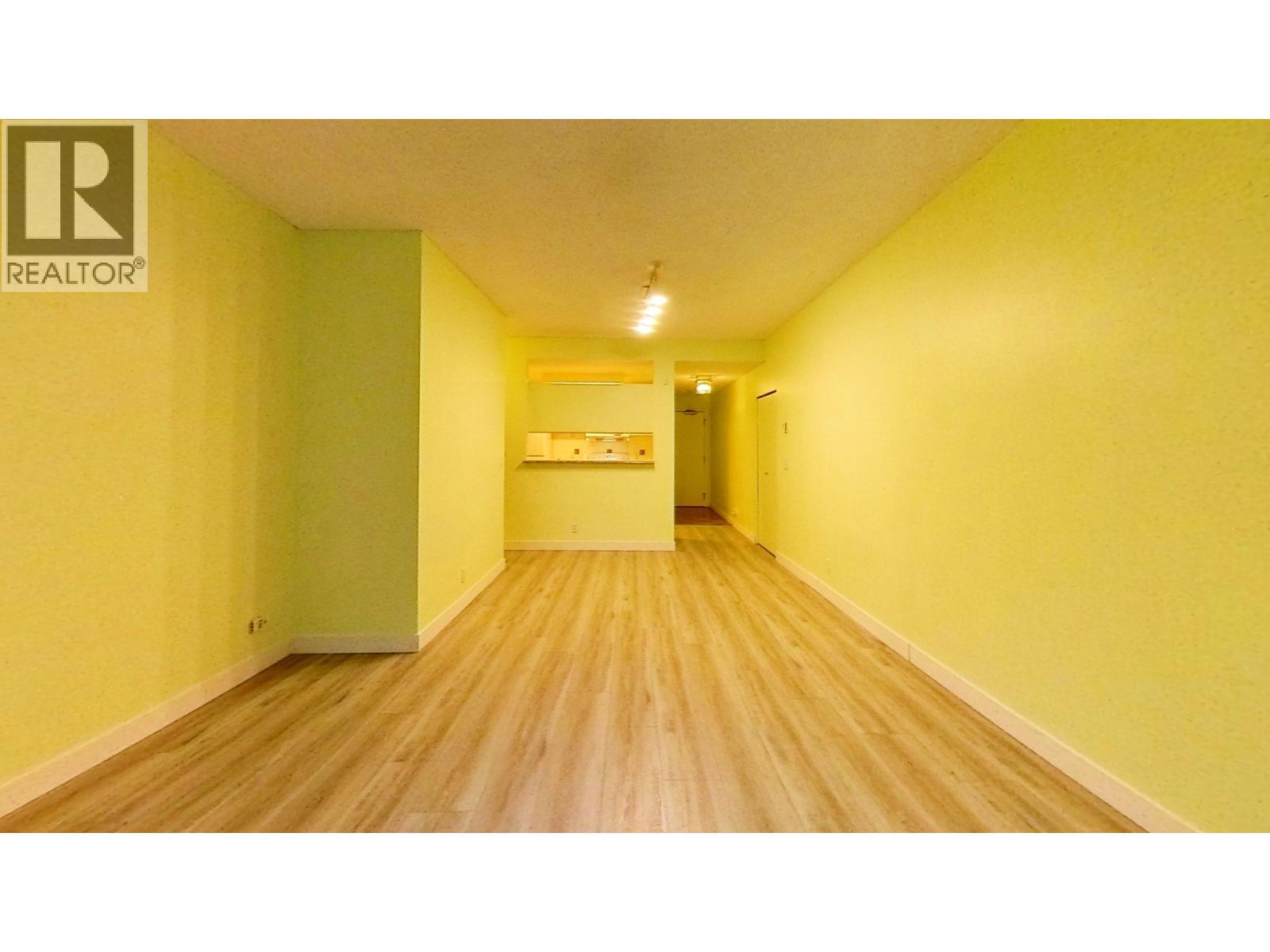 A long hallway with a green door and a Realtor sign on the wall.