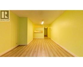 A long hallway with a green door and a Realtor sign on the wall.