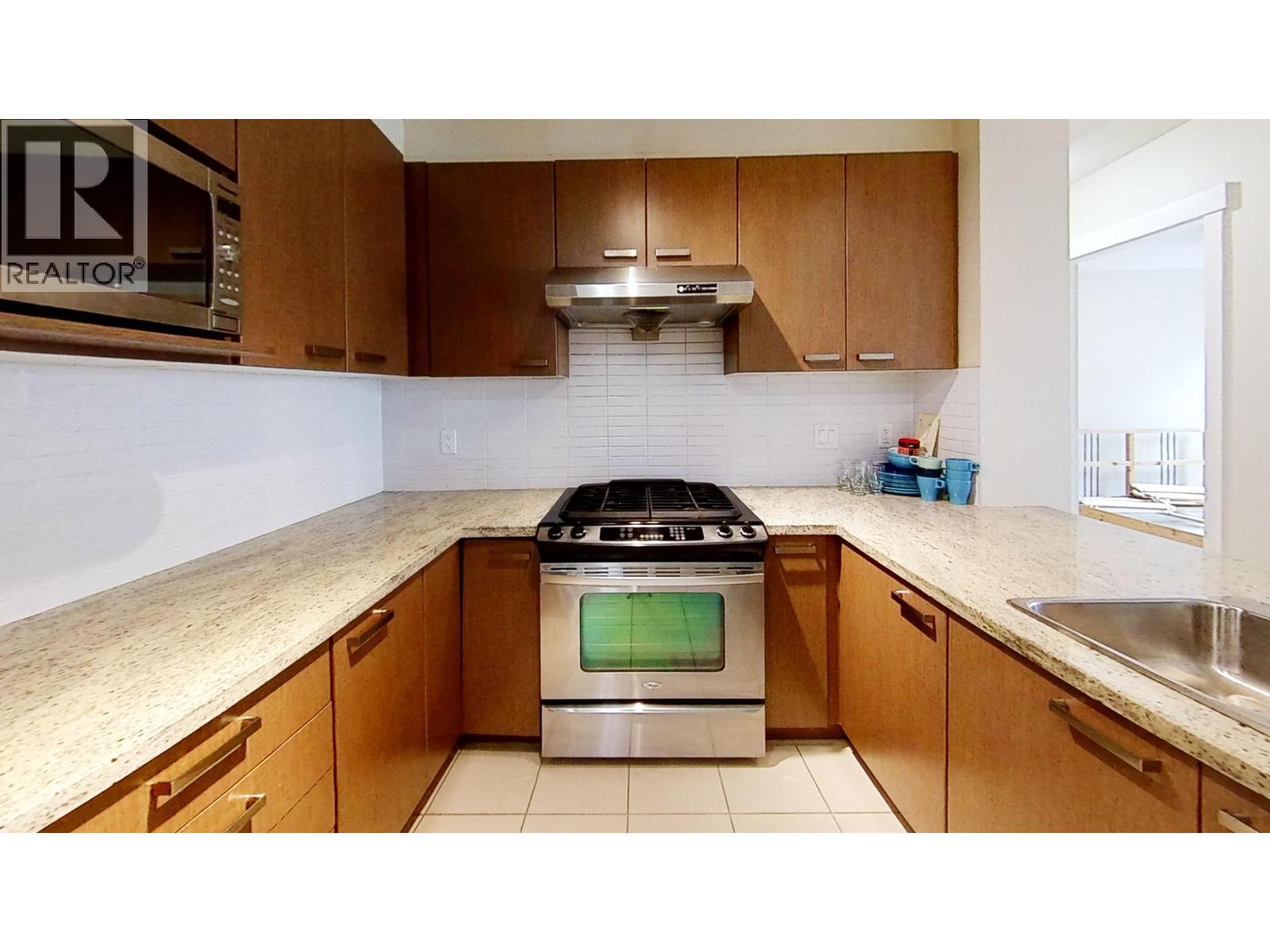 A kitchen with a stove top oven and wooden cabinets.