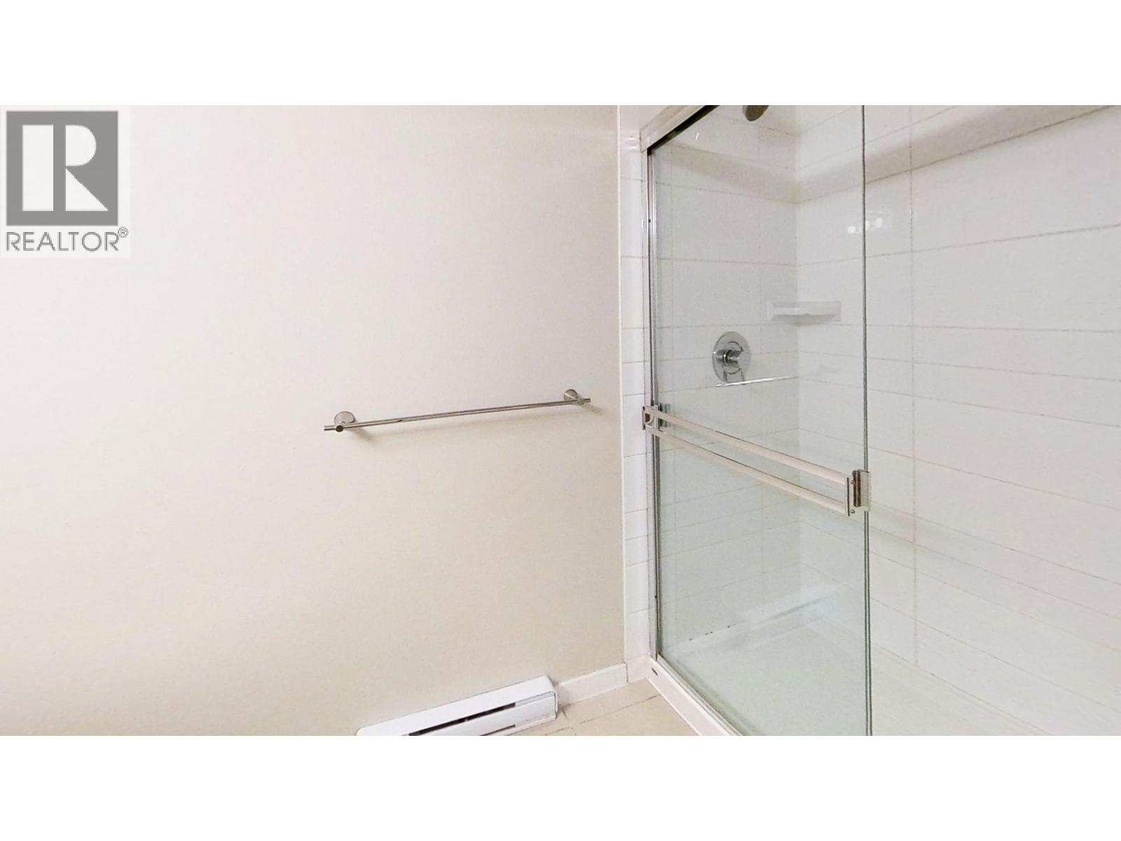 A white tiled bathroom with a glass shower door.