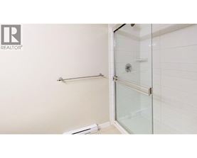 A white tiled bathroom with a glass shower door.