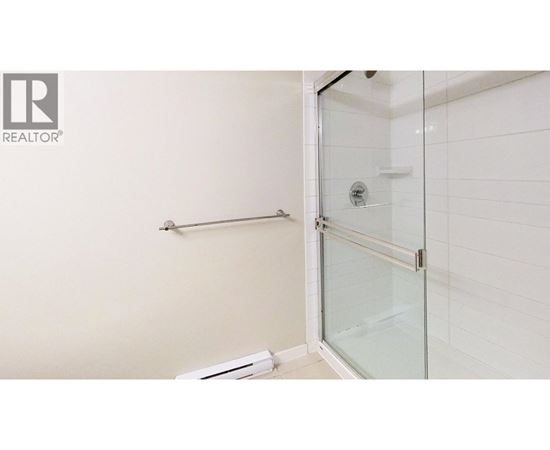 A white tiled bathroom with a glass shower door.