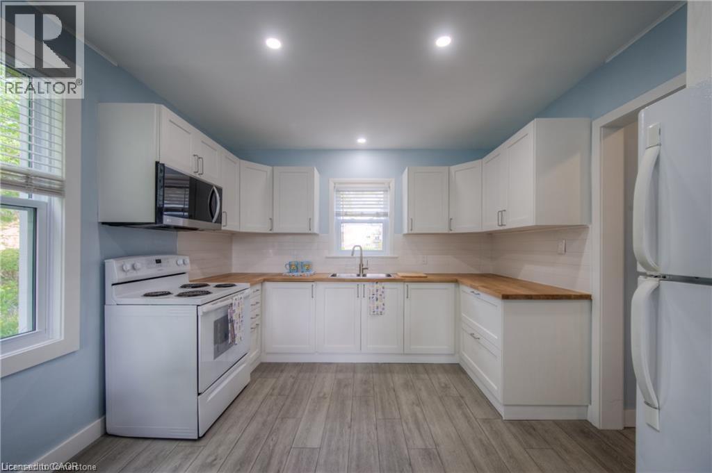 A kitchen with white cabinets and a white stove top oven.