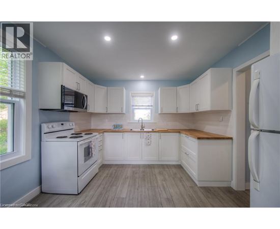 A kitchen with white cabinets and a white stove top oven.