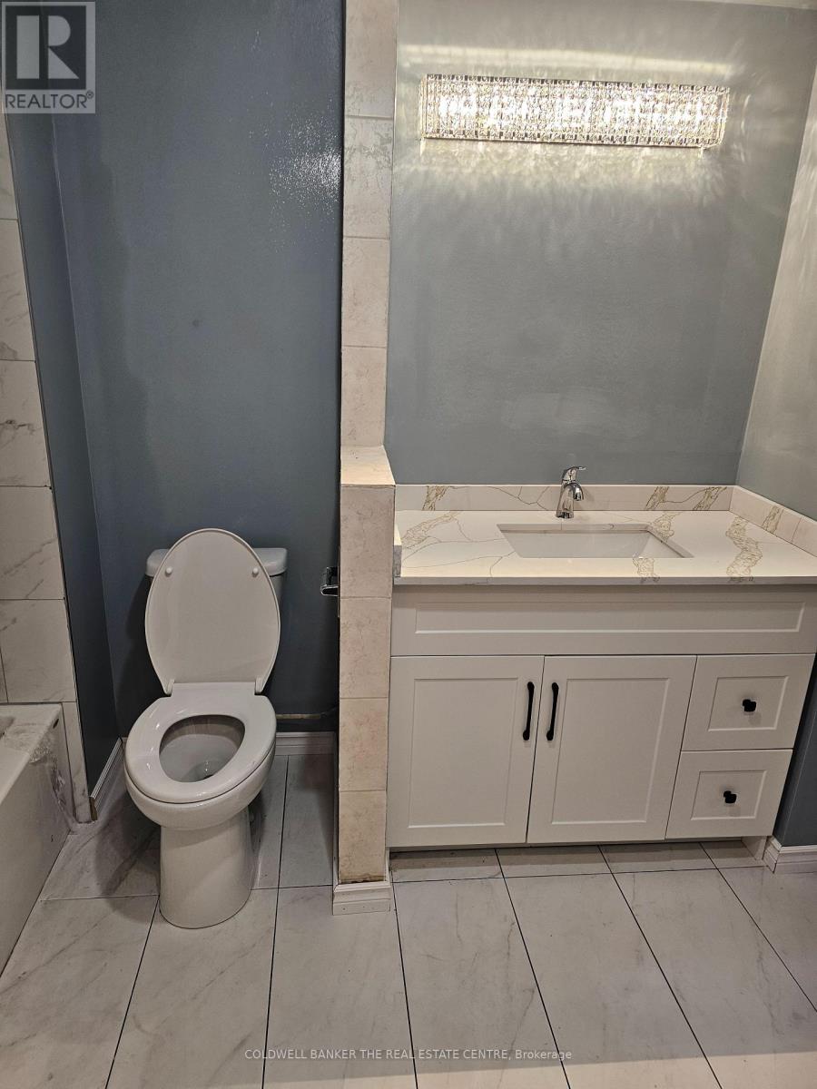 A white toilet sits in a bathroom with a marble counter top.