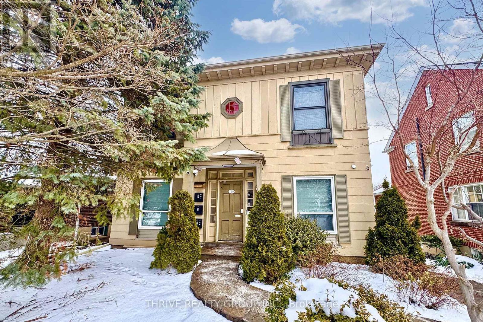 A house with a brown door and a sign that says "Thrive Realty" on the front.