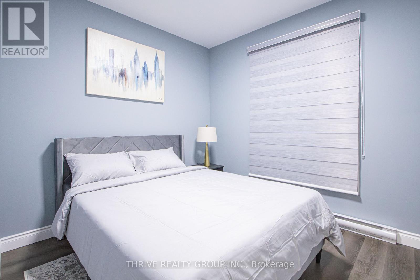 A bedroom with a large bed and a painting on the wall.