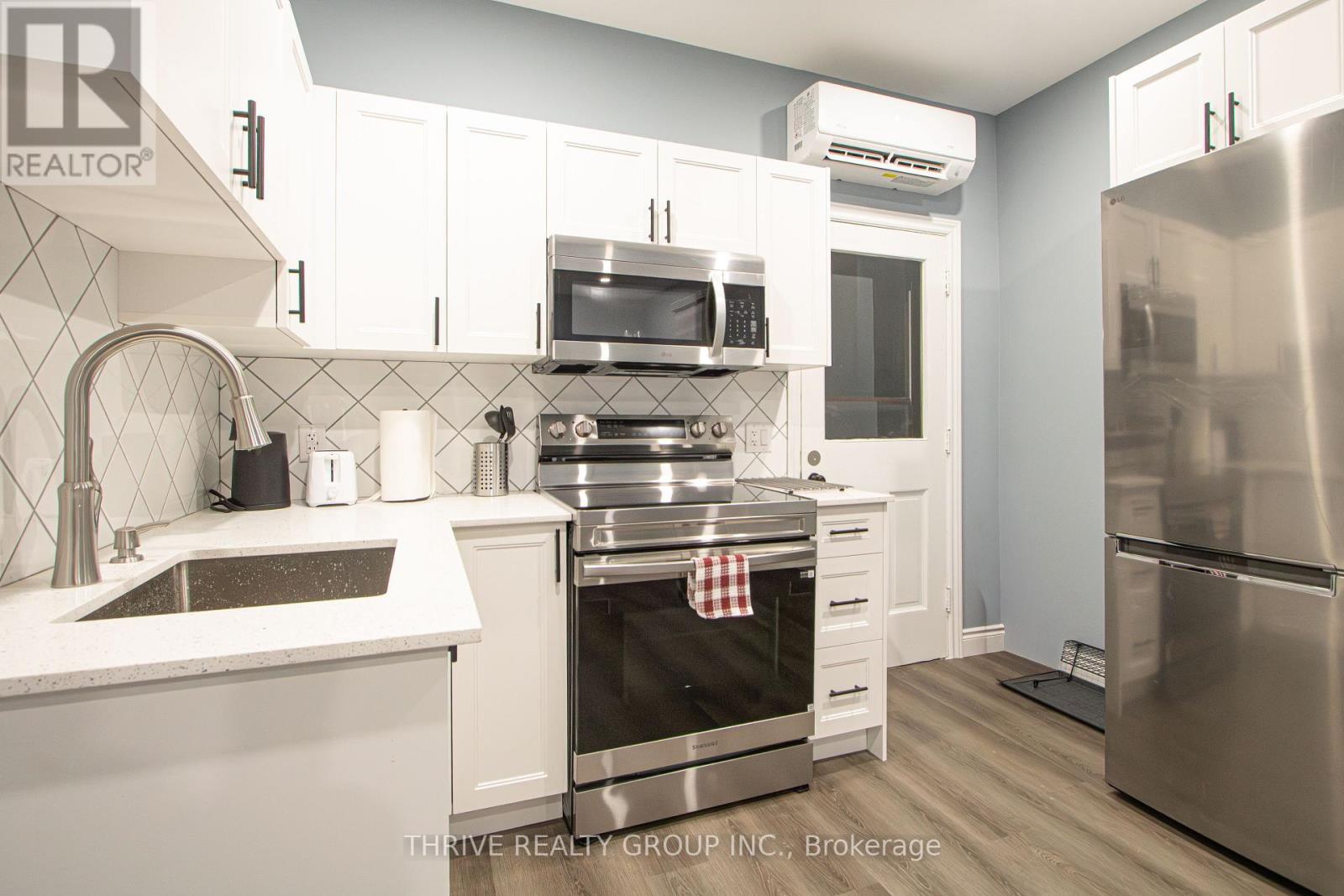 A kitchen with a stainless steel refrigerator and white cabinets.