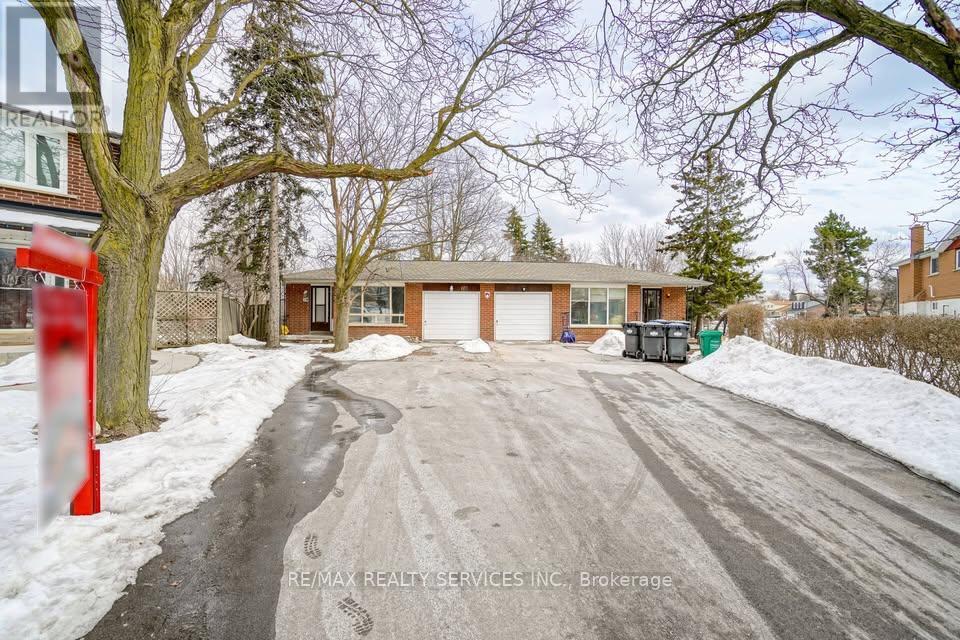 A snowy street with a red post and a house with a white garage door.