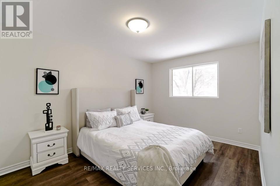 A bedroom with a bed, nightstand, and a window.