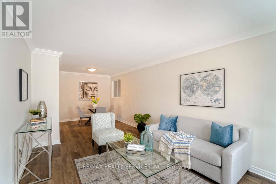 A living room with a grey couch, a glass coffee table, and a painting on the wall.