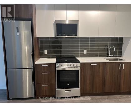 A modern kitchen with a stainless steel refrigerator, a microwave above the stove, and wooden cabinets.