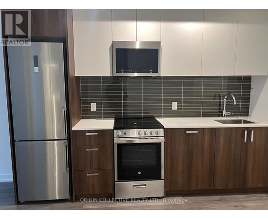 A modern kitchen with a stainless steel refrigerator, a microwave above the stove, and wooden cabinets.