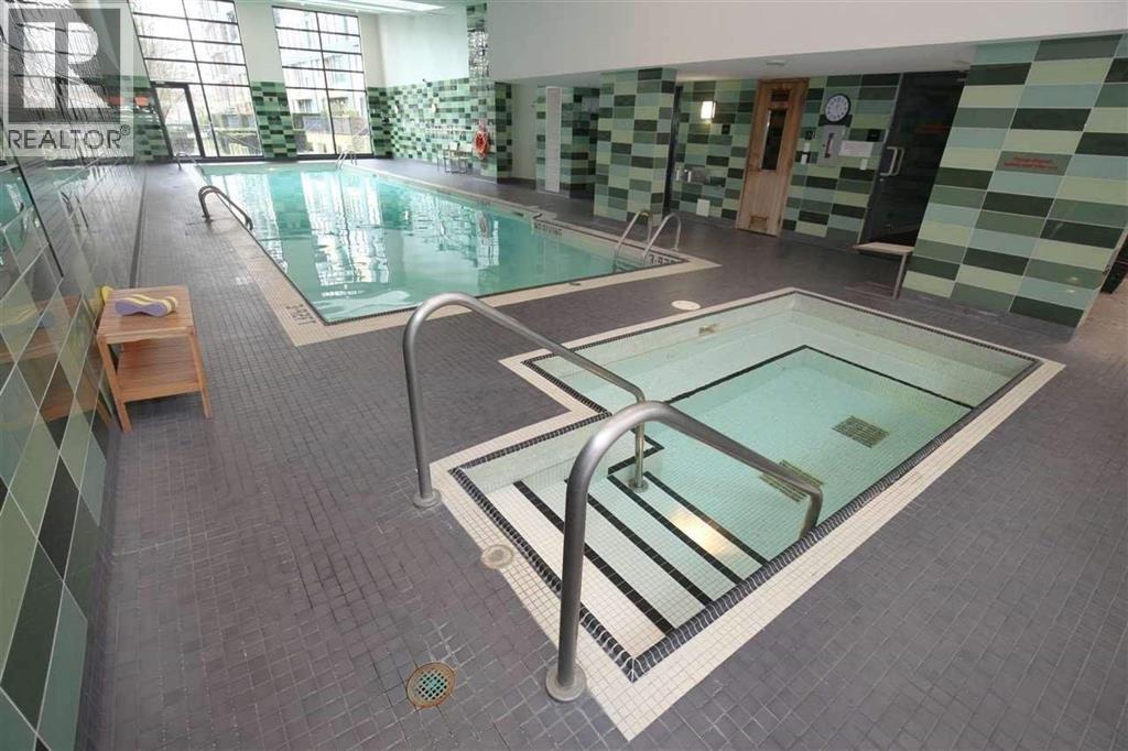 A swimming pool in a tiled room with a glass divider.