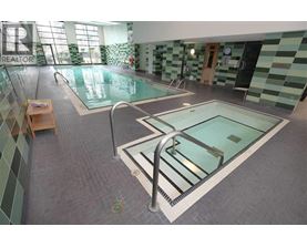 A swimming pool in a tiled room with a glass divider.