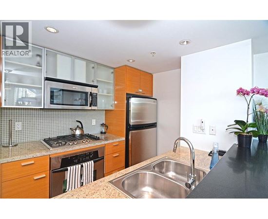 A kitchen with a stove, refrigerator, and sink.