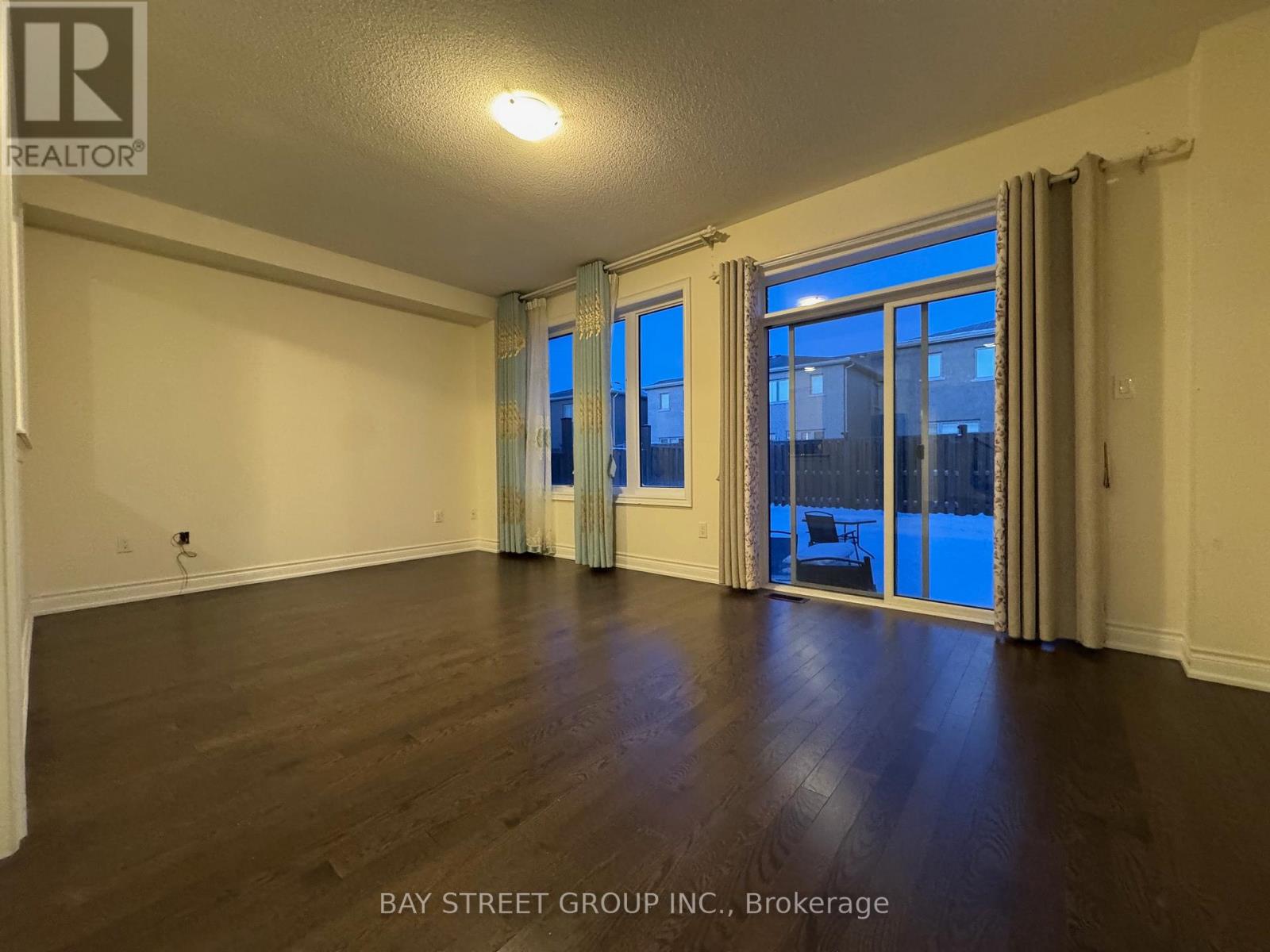 A spacious room with wooden floors and a large window with a view of the city.