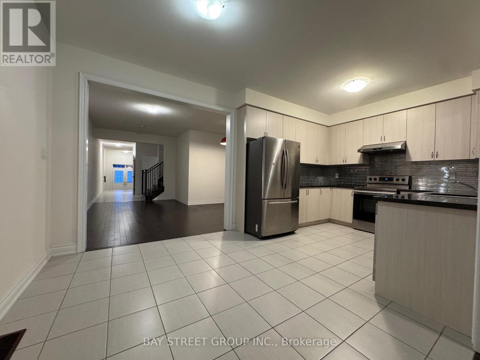 A kitchen with white tiles on the floor and a refrigerator in the middle.