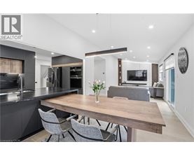 A modern kitchen with a wooden table and grey chairs.